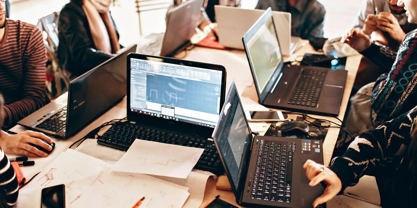 Technology professionals collaborating around laptop computers